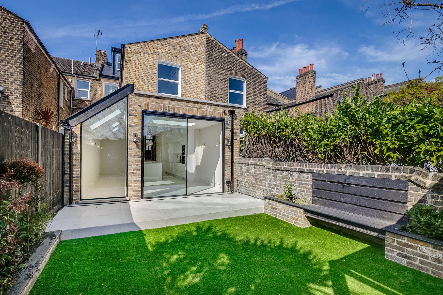 Rear extension with a glass corner and slim black sliding doors onto the garden