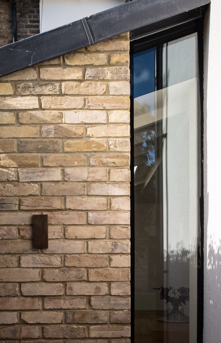 Black aluminium sliding door frame against yellow London brick