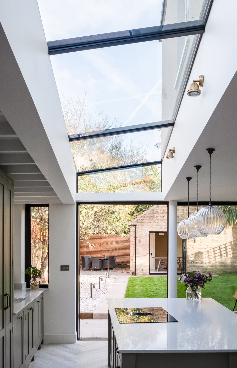 Kitchen under a long glass rooflight opening to the garden