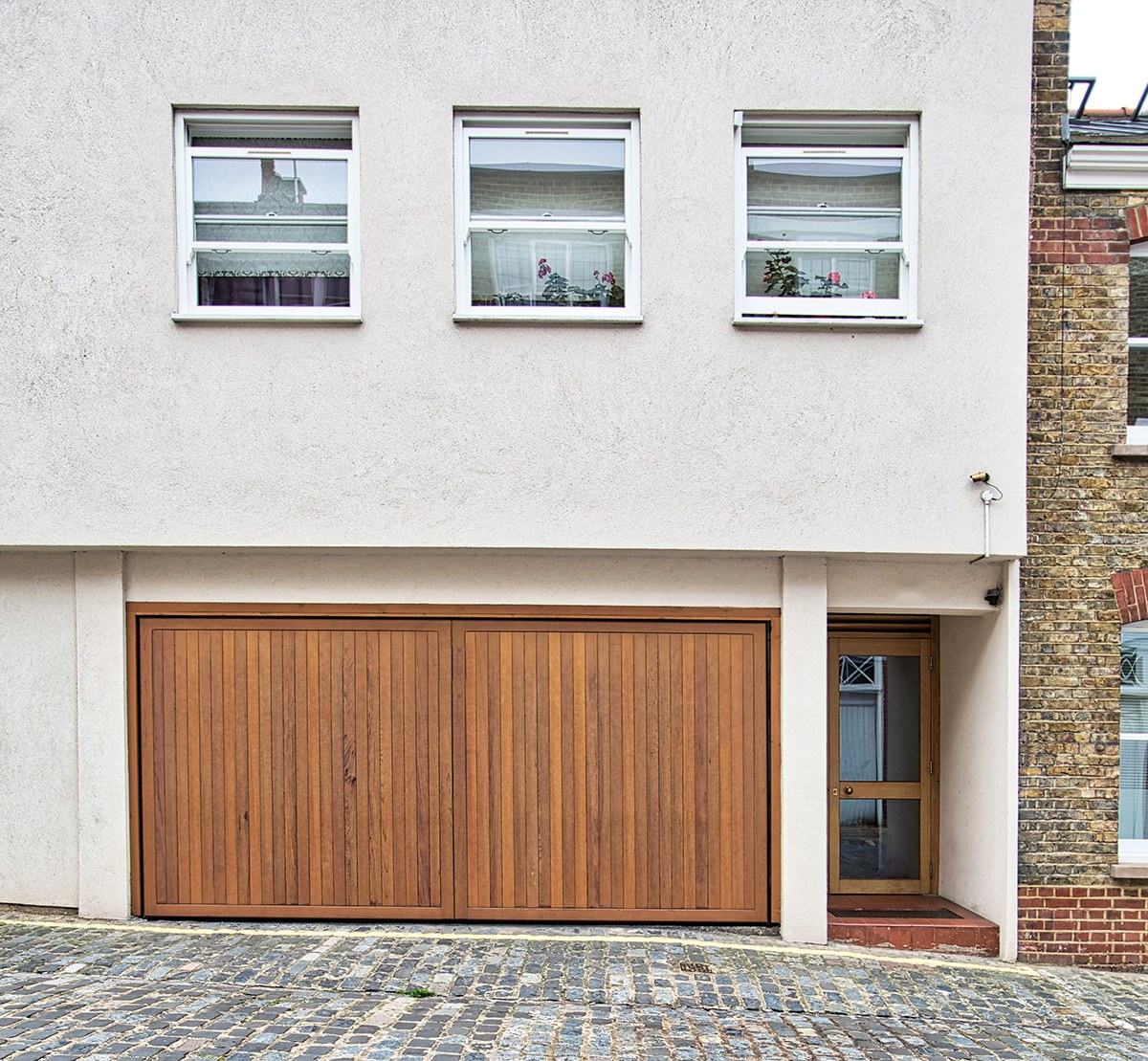 Mews house with white timber windows, a cedar garage door and a matching side door